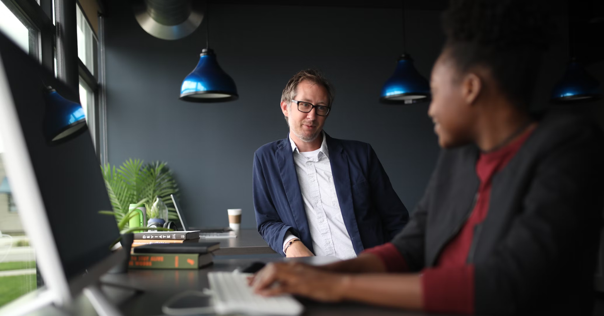 man standing on a standing chair having a chat with coworker