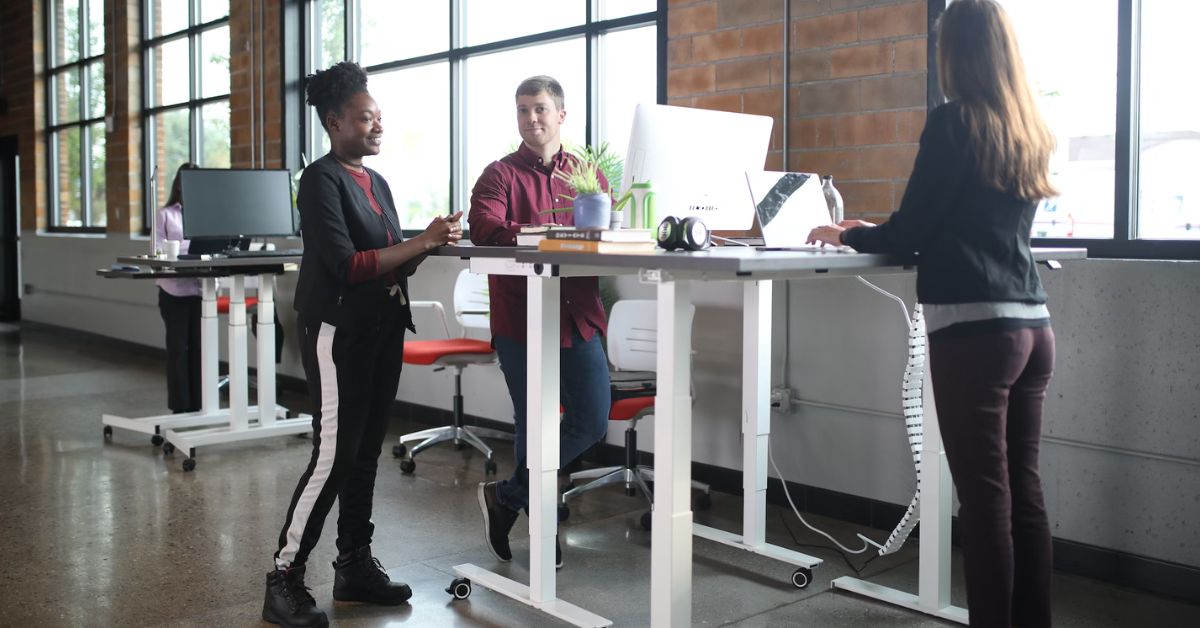 employees chatting at work while standing at standing desks