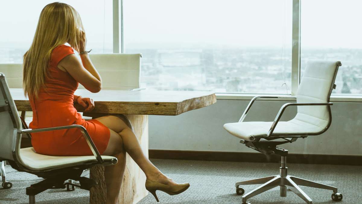 A woman talking through a phone while sitting on an office chair.