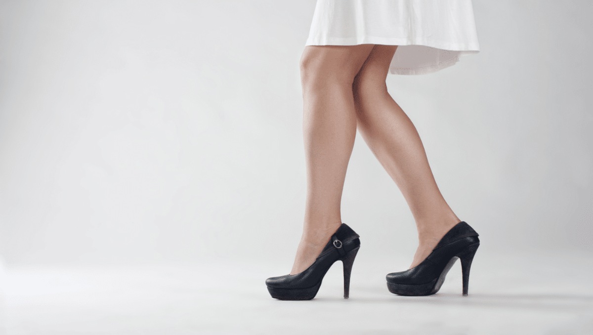 The legs of a woman wearing black high heels.