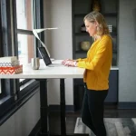 Woman standing at an electric height-adjustable desk, showcasing power usage