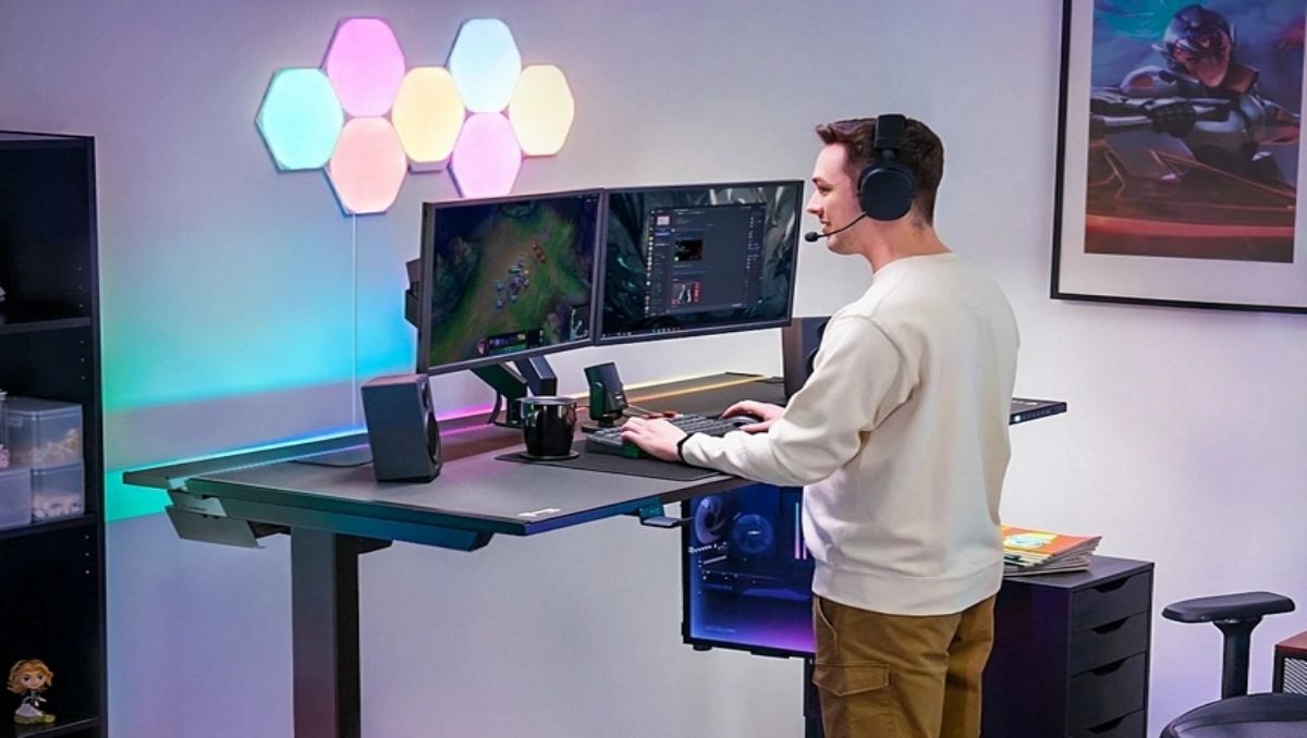 A guy playing a video game using a standing desk.