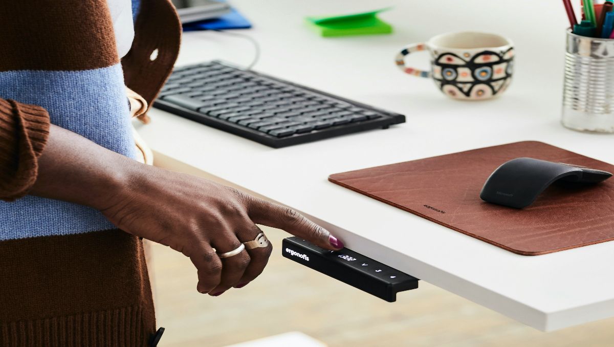 A person clicking on the black box mod of a standing desk.