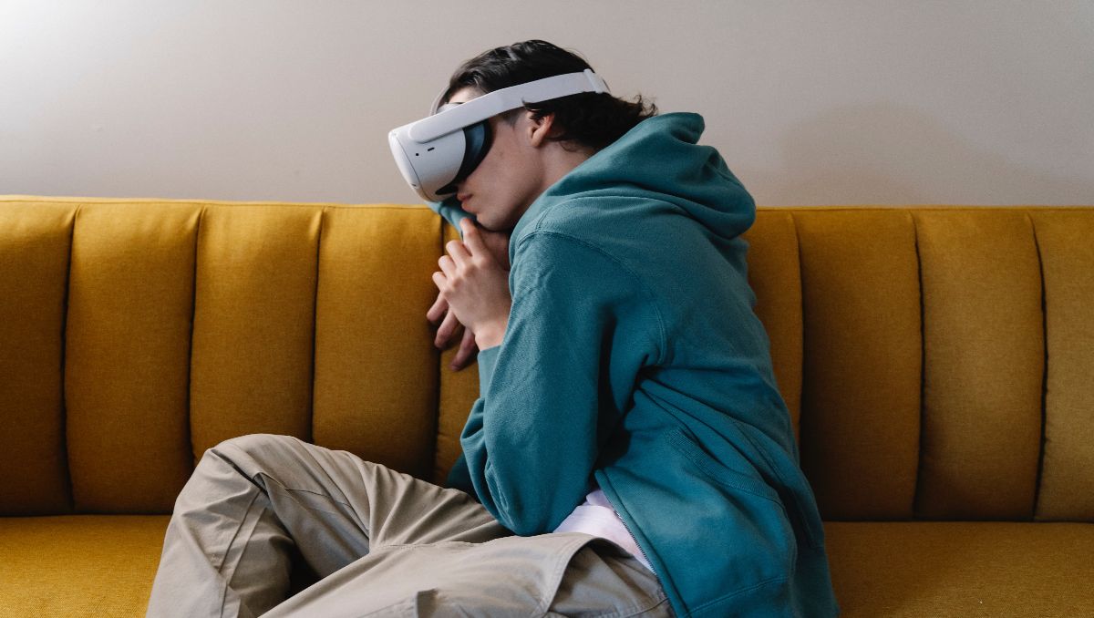 A teenage man resting on the couch wearing a VR.