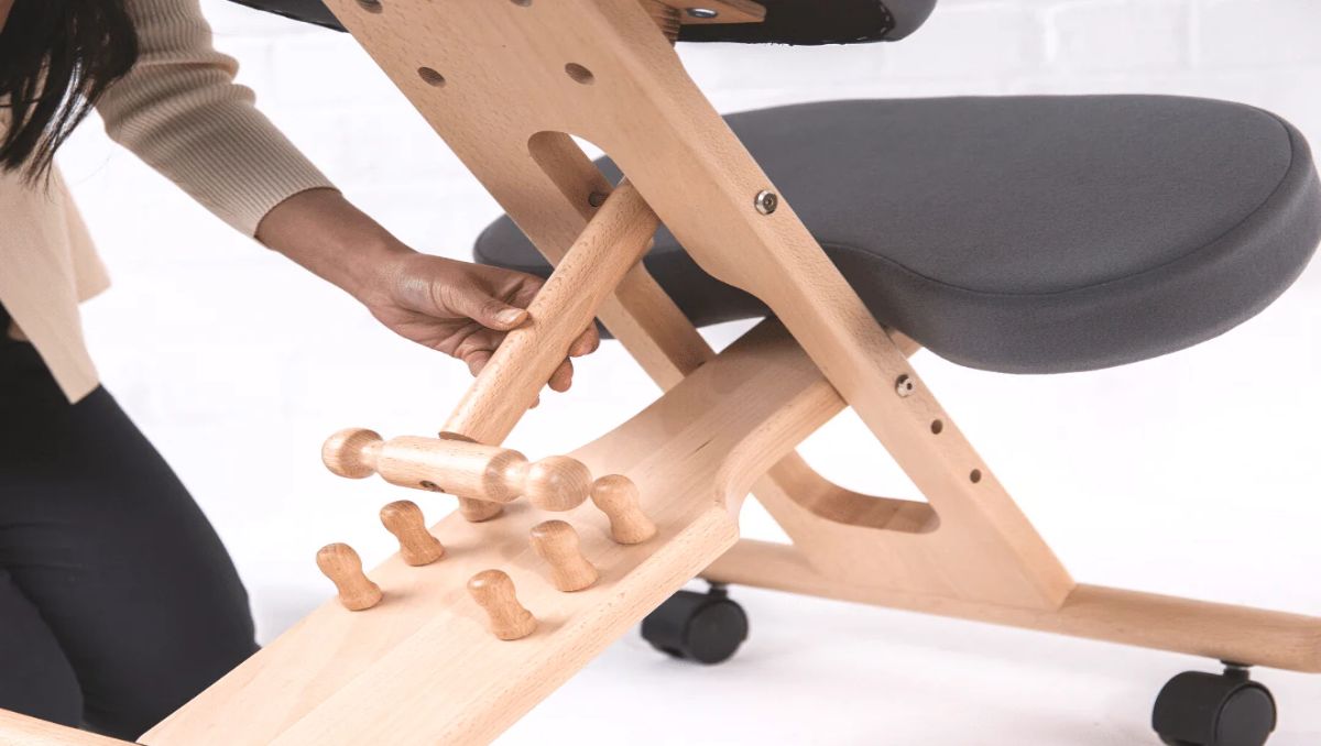 A woman adjusting the height of the kneeling chair.