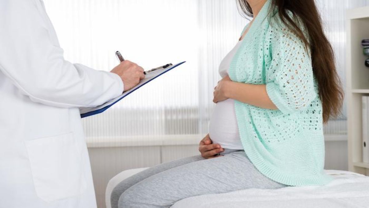 A pregnant woman talking to a doctor inside the clinic.
