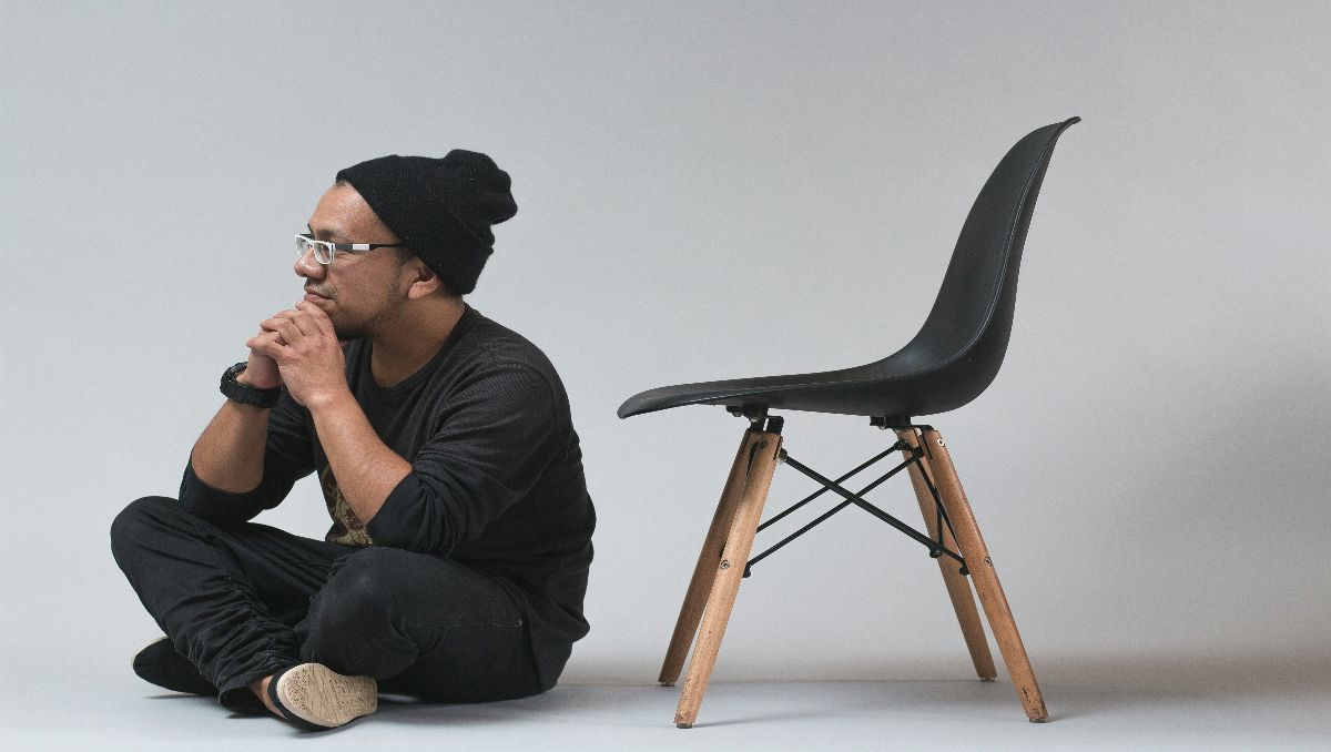 A man sitting on the floor beside an office chair