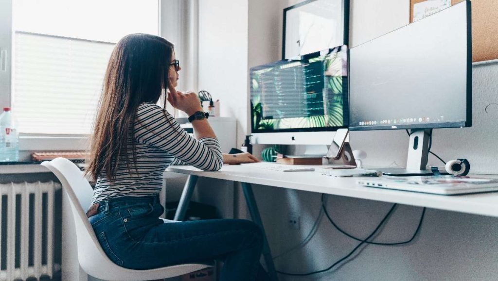 A girl sitting in an ergonomic chair facing the desktop.