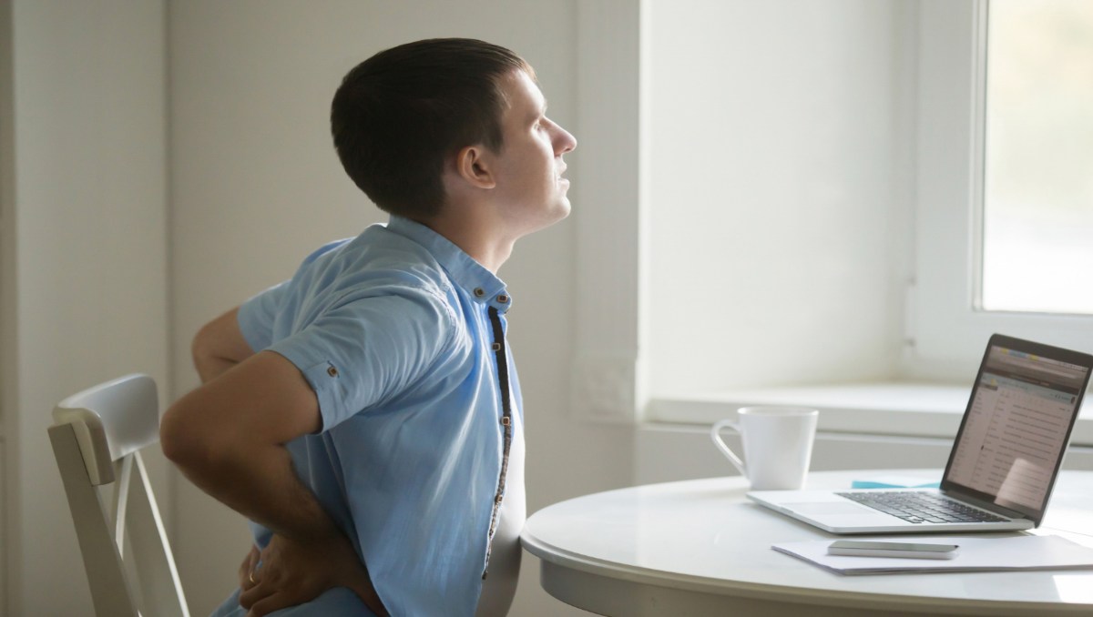 Man with laptop, stretching with lower back pain