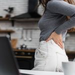 Girl having sore back while standing beside office chair