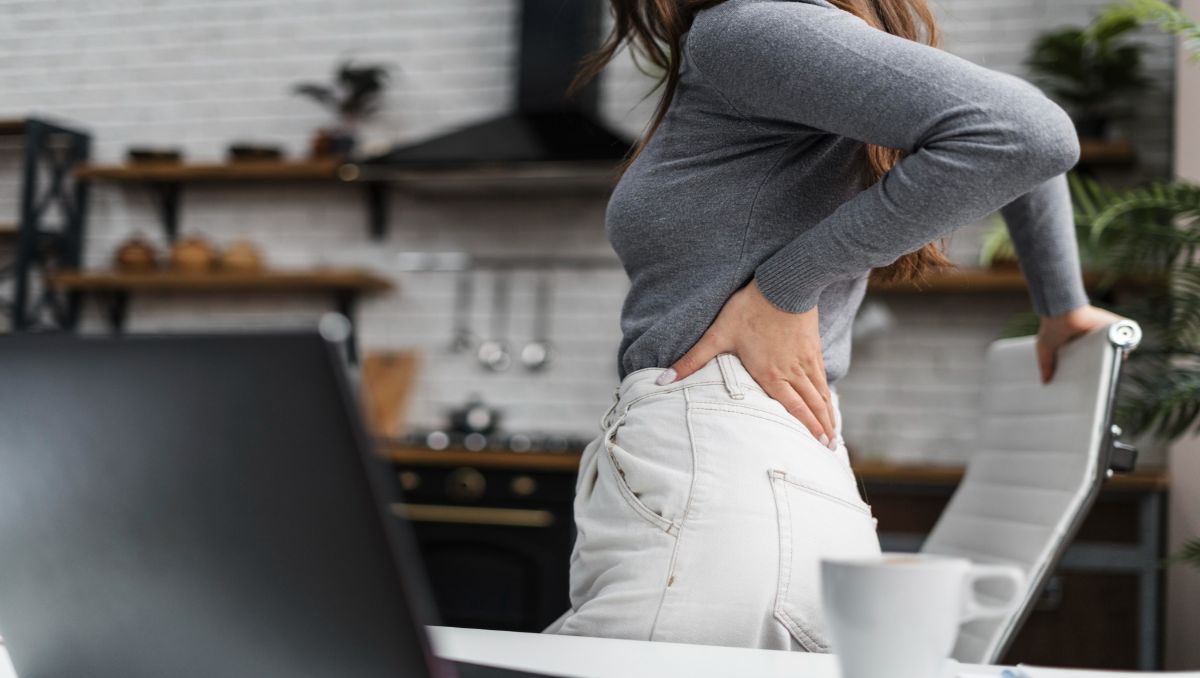 Girl having sore back while standing beside office chair