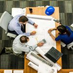 Office workers drafting project while sitting on drafting chair and office chairs