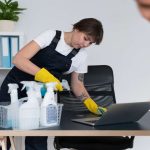 Two women cleaning mesh chair in the office