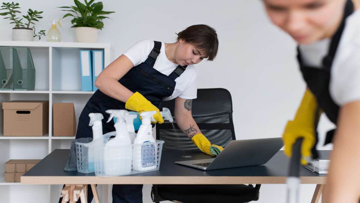 Two women cleaning mesh chair in the office