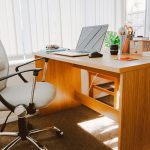 a high back chair next to a wooden desk in office