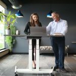 A man and woman employee working on a standing desk