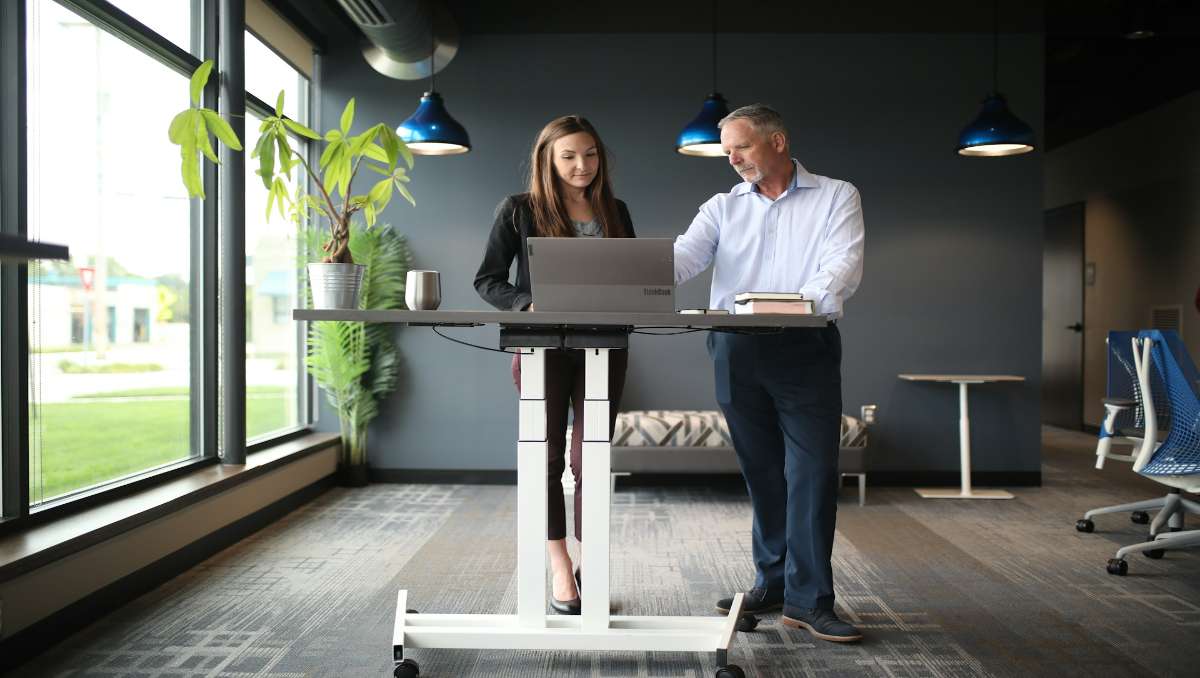 A man and woman employee working on a standing desk