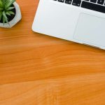Desk showing wood grain with laptop and headphone