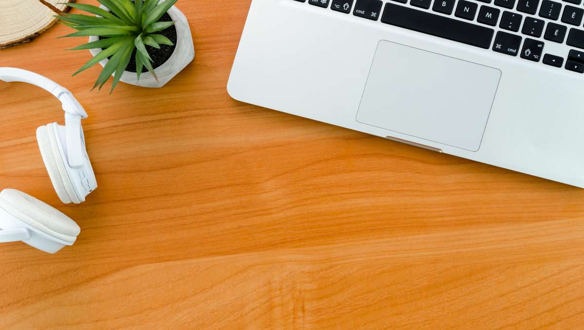 Desk showing wood grain with laptop and headphone