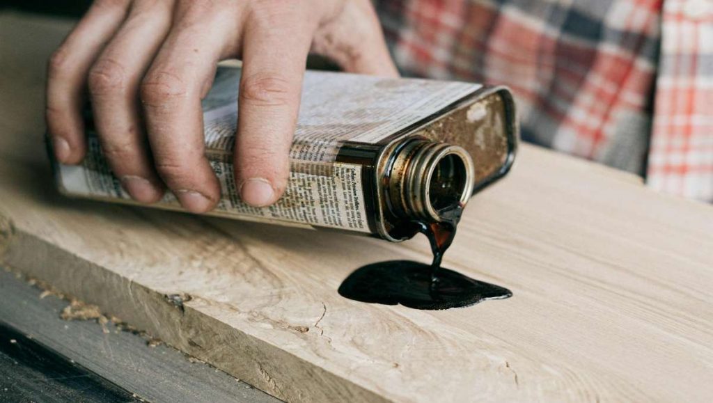 Hand pouring a bottle of wood finishing