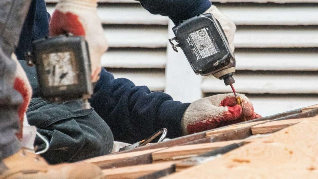 Worker using power drill on wood