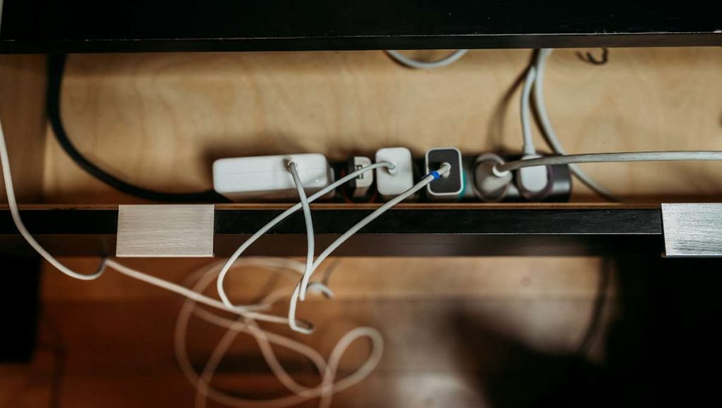 cable management accessories Cables and chargers under a wooden desk