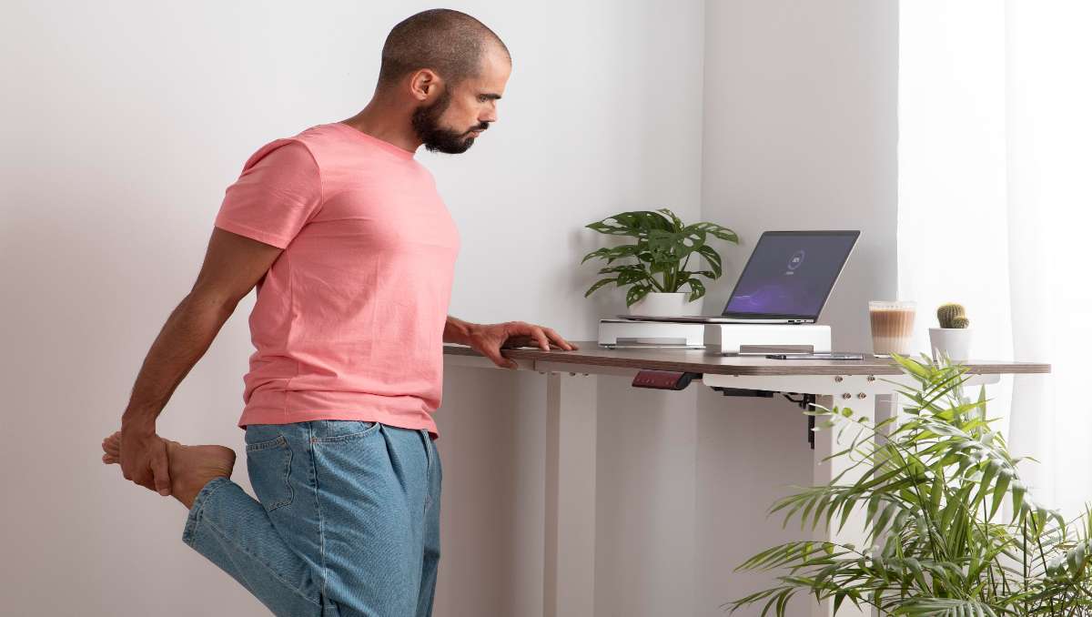 Man working on his standing desk at home while stretching