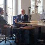 Two men talking in the executive office with wooden desk