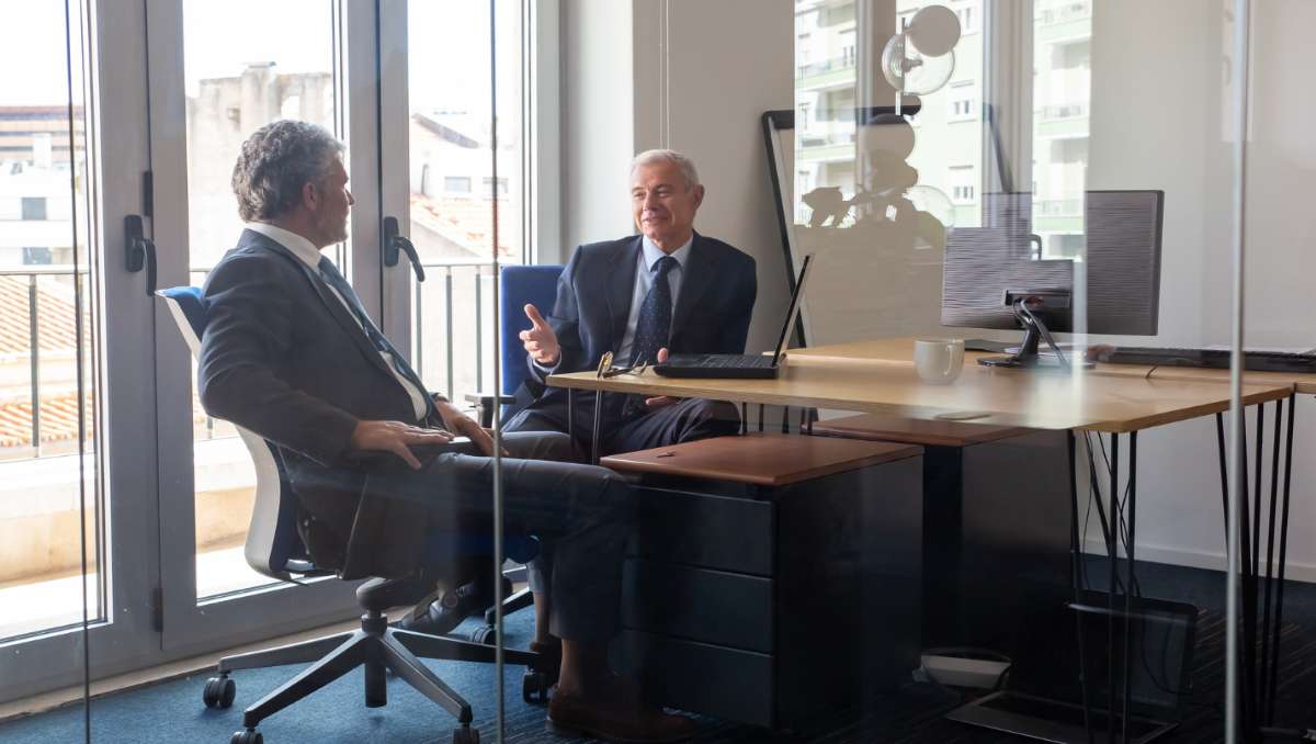 Two men talking in the executive office with wooden desk