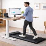 Man working on standing desk while doing exercise with under desk walking pad equipment