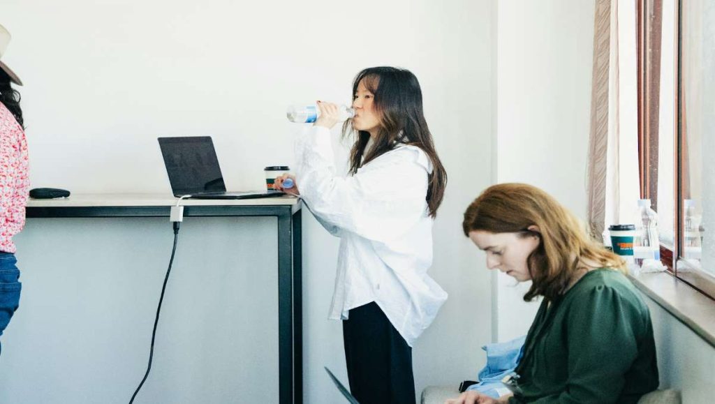 Woman drinking water while working on a standing desk