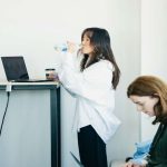Woman drinking water while working on a standing desk