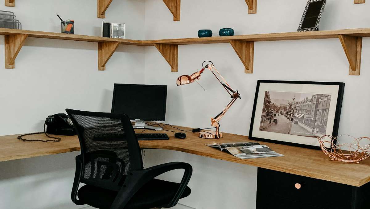 A corner desk setup with laptop and office chair