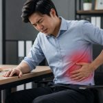 Man having rib pain while sitting on a desk